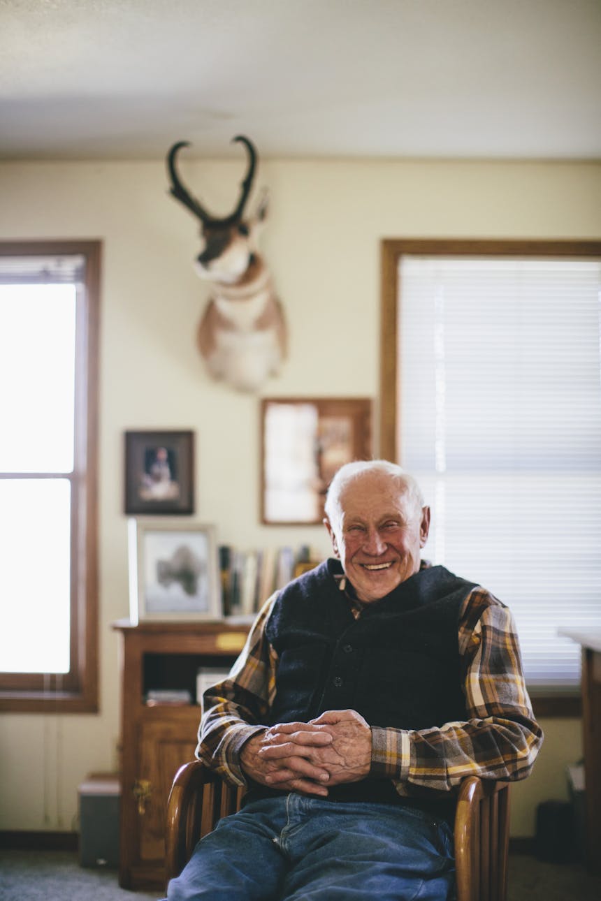 Portrait of Jim sitting in chair in front of mounted trophy animal