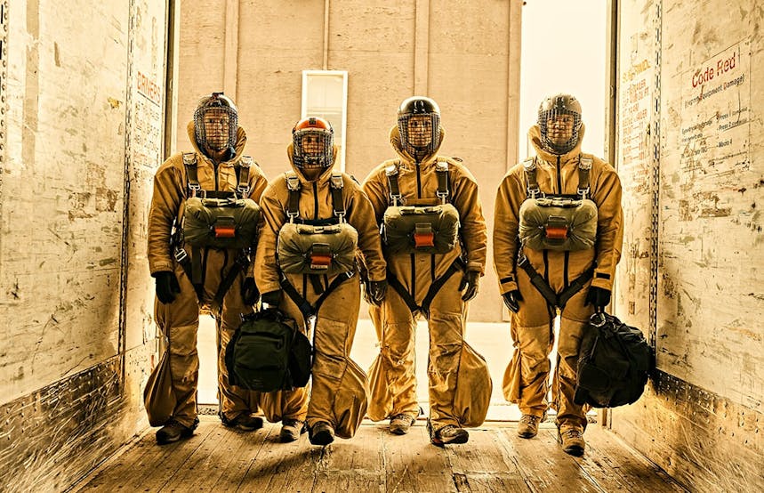 four smokejumpers in full uniform standing in white room